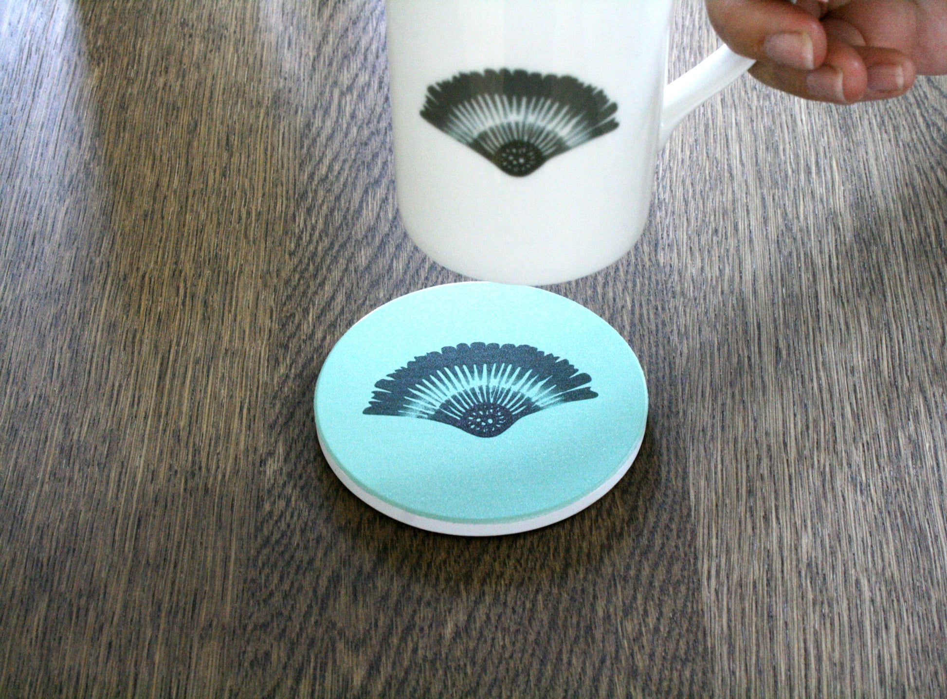 Glasunderlägg Solfjäder Keramik Skogsgrön (4-pack), miljöbild på bord i valnöt med kopp