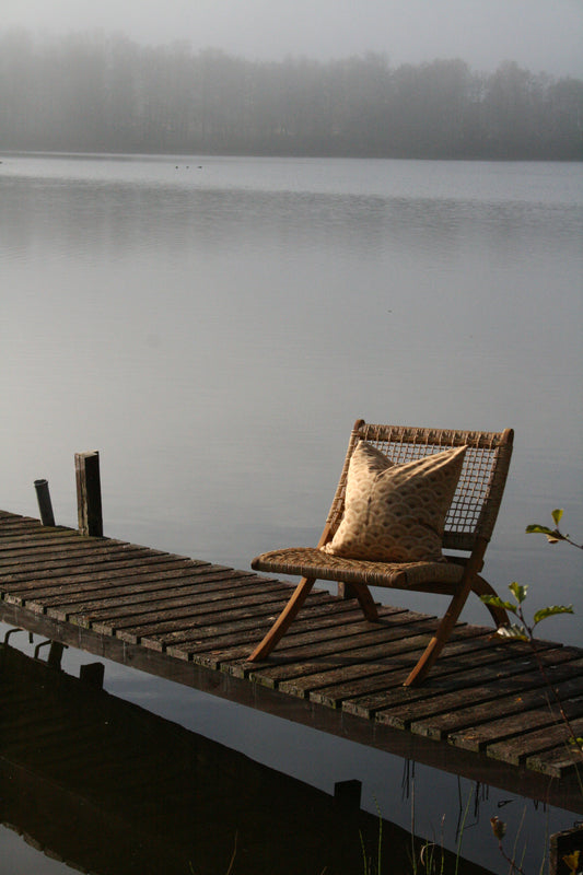 Kuddfodral Vågor Linneblandning Soft Gold 50x50, miljöbild. Kudde på stol ute på brygga.