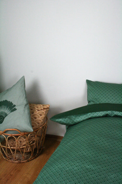 Påslakanset Vågor Bomullssatin Skogsgrön 210×150 cm, miljöbild. Bäddad säng med nedvikt kant, korg med prydnadskuddar