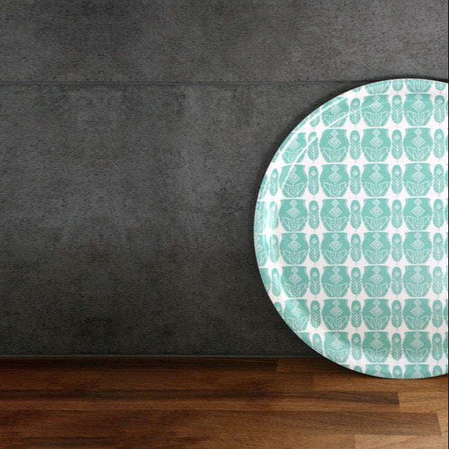 Mönstrad serveringsbricka i turkos och vit mot antracitgrått kakel och bänkskiva i valnöt.